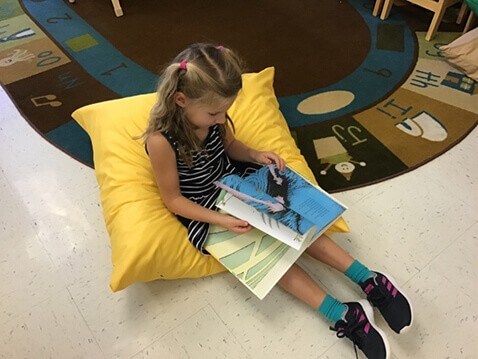 Young girl reading in preschool